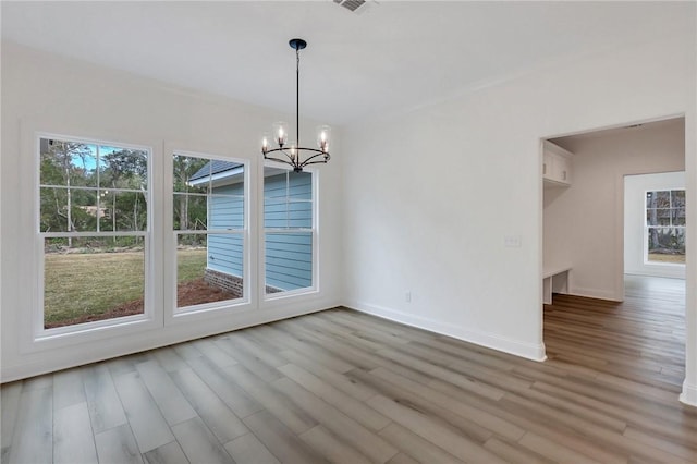 unfurnished dining area with an inviting chandelier and light hardwood / wood-style flooring