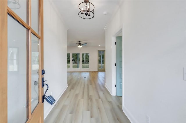 hallway with light hardwood / wood-style floors and an inviting chandelier