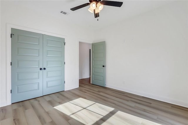 unfurnished bedroom with light wood-type flooring, a closet, and ceiling fan