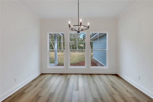 unfurnished dining area with a chandelier and light hardwood / wood-style flooring