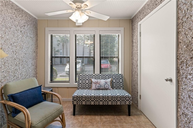 living area with ceiling fan, a healthy amount of sunlight, light tile patterned flooring, and crown molding