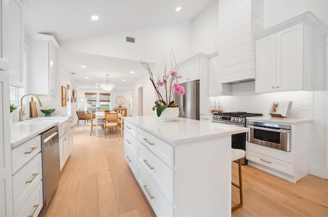301 Kelsall Ave, Saint Simons Island, GA 31522 - kitchen with appliances with stainless steel finishes, light wood-style floors, white cabinetry, recessed lighting, and lofted ceiling