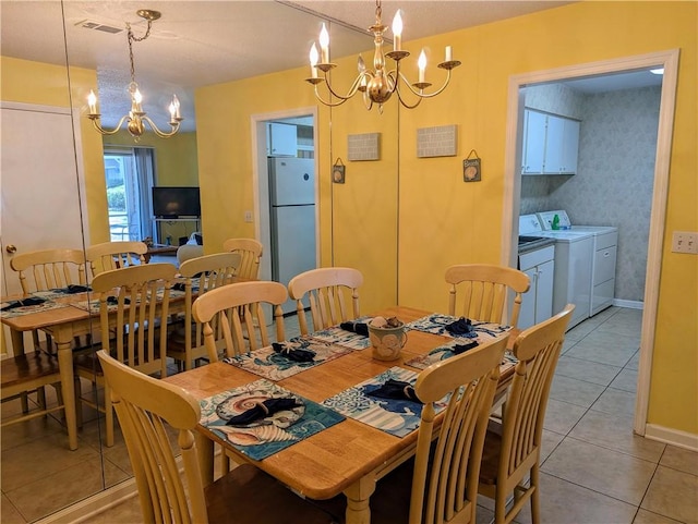 tiled dining space featuring washer and dryer and an inviting chandelier