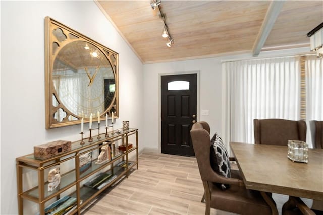 interior space featuring wood ceiling, rail lighting, vaulted ceiling with beams, a wealth of natural light, and light hardwood / wood-style flooring