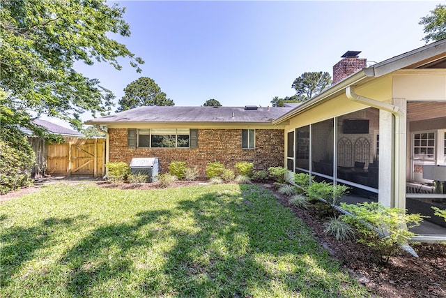 rear view of house featuring a lawn and a sunroom