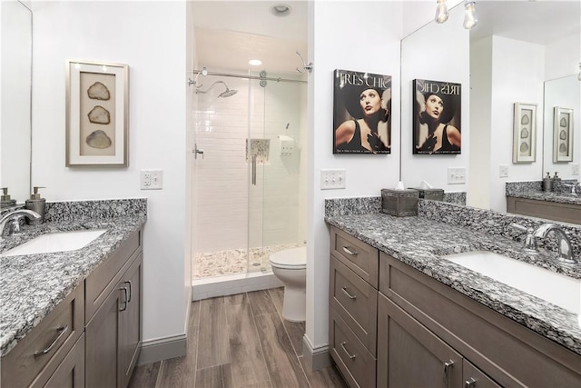 bathroom featuring vanity, a shower with shower door, and toilet