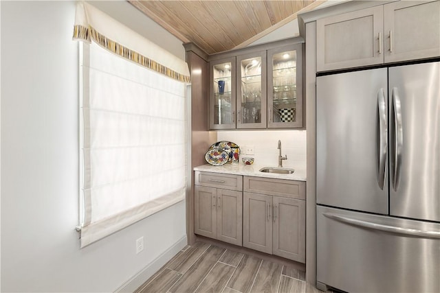 kitchen with sink, lofted ceiling, tasteful backsplash, stainless steel refrigerator, and wood ceiling