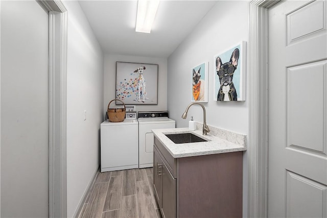 clothes washing area featuring sink, cabinets, and washing machine and dryer