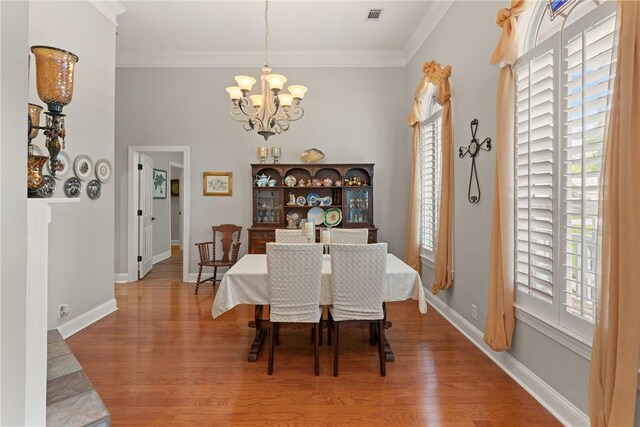 dining space featuring crown molding, visible vents, wood finished floors, and a chandelier