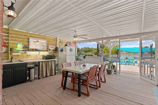 wooden terrace featuring fence, ceiling fan, outdoor dining space, and a sink