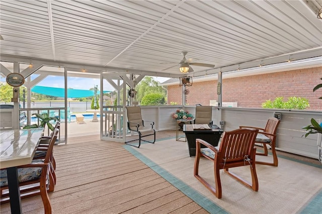 wooden deck with outdoor dining area, a patio area, a fenced in pool, a ceiling fan, and fence