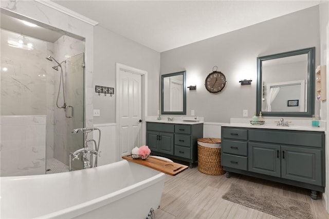 full bathroom featuring a sink, two vanities, a freestanding bath, and a marble finish shower