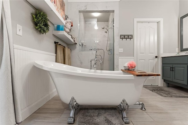 full bath featuring a freestanding bath, a shower stall, wainscoting, and wood finished floors