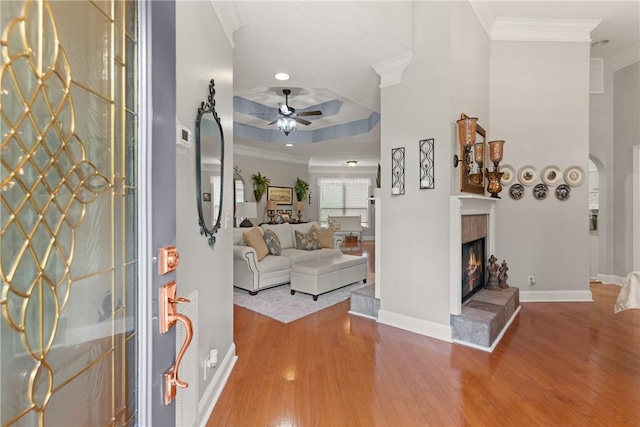 entrance foyer with baseboards, wood finished floors, a ceiling fan, and crown molding