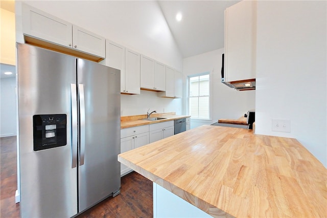 kitchen with lofted ceiling, white cabinets, stainless steel appliances, and wood counters