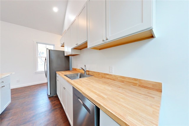 kitchen with wood counters, appliances with stainless steel finishes, white cabinetry, and sink