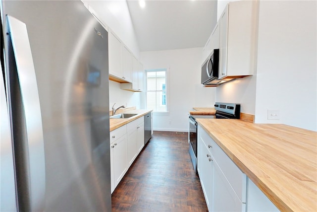 kitchen with wooden counters, stainless steel appliances, and white cabinetry