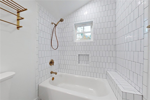 bathroom featuring tiled shower / bath combo and toilet