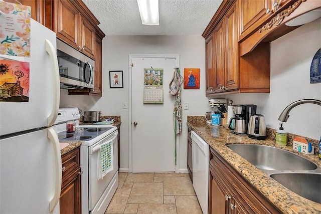 132 S Island Square Dr, Saint Simons Island, GA 31522 - kitchen with white appliances, stone tile floors, brown cabinetry, a textured ceiling, and light stone countertops