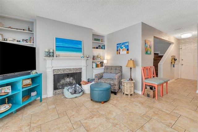 132 S Island Square Dr, Saint Simons Island, GA 31522 - sitting room featuring built in shelves, stairway, a textured ceiling, a tiled fireplace, and stone finish floors