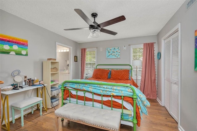 132 S Island Square Dr, Saint Simons Island, GA 31522 - bedroom featuring a closet, wood finished floors, a textured ceiling, ensuite bath, and ceiling fan