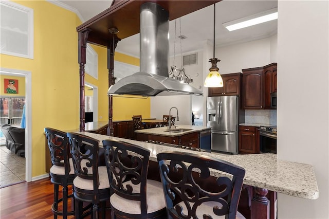 kitchen featuring sink, hanging light fixtures, appliances with stainless steel finishes, kitchen peninsula, and island exhaust hood