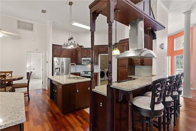 kitchen with sink, appliances with stainless steel finishes, island range hood, separate washer and dryer, and kitchen peninsula