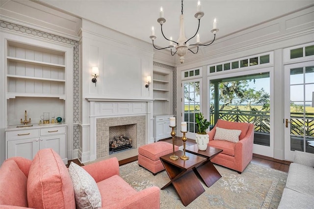144 Point Ln, Saint Simons Island, GA 31522 - living room with built in shelves, crown molding, a chandelier, a fireplace with flush hearth, and wood finished floors