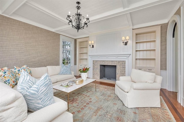 144 Point Ln, Saint Simons Island, GA 31522 - living room featuring wood finished floors, built in features, a chandelier, beam ceiling, and a fireplace with flush hearth