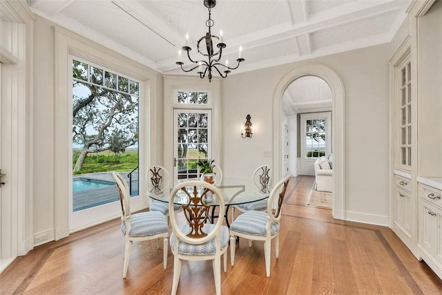 144 Point Ln, Saint Simons Island, GA 31522 - dining room with light wood-style floors, arched walkways, a chandelier, plenty of natural light, and beamed ceiling