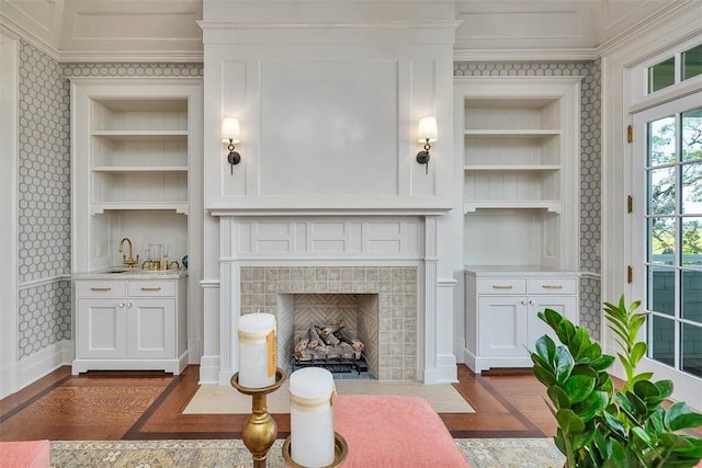 144 Point Ln, Saint Simons Island, GA 31522 - living area featuring crown molding, built in features, wallpapered walls, a brick fireplace, and dark wood-type flooring