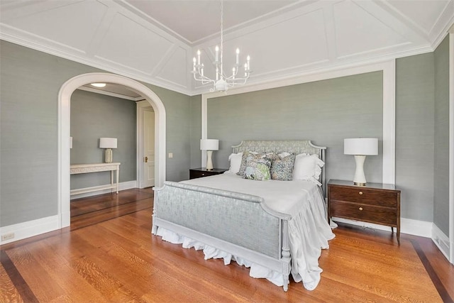 144 Point Ln, Saint Simons Island, GA 31522 - bedroom with a chandelier, wood finished floors, arched walkways, baseboards, and ornamental molding