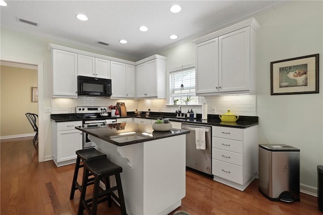 11 Niblick Ct, Saint Simons Island, GA 31522 - kitchen with appliances with stainless steel finishes, ornamental molding, white cabinets, tasteful backsplash, and dark wood-type flooring
