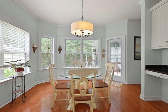 11 Niblick Ct, Saint Simons Island, GA 31522 - dining room featuring light wood-type flooring, a chandelier, baseboards, ornamental molding, and a textured ceiling