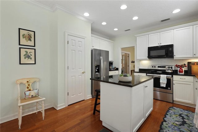 11 Niblick Ct, Saint Simons Island, GA 31522 - kitchen featuring appliances with stainless steel finishes, ornamental molding, dark countertops, white cabinetry, and backsplash