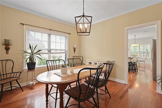 11 Niblick Ct, Saint Simons Island, GA 31522 - dining space featuring wood-type flooring, healthy amount of natural light, a chandelier, a textured ceiling, and crown molding