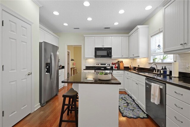 11 Niblick Ct, Saint Simons Island, GA 31522 - kitchen featuring appliances with stainless steel finishes, backsplash, a sink, ornamental molding, and dark countertops