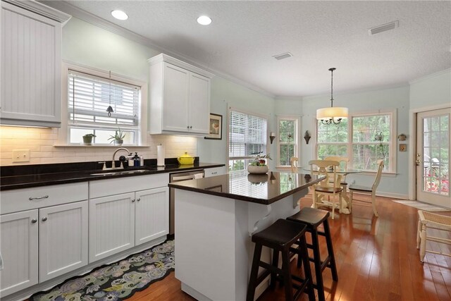 11 Niblick Ct, Saint Simons Island, GA 31522 - kitchen featuring a sink, crown molding, dark wood-type flooring, decorative backsplash, and dark countertops