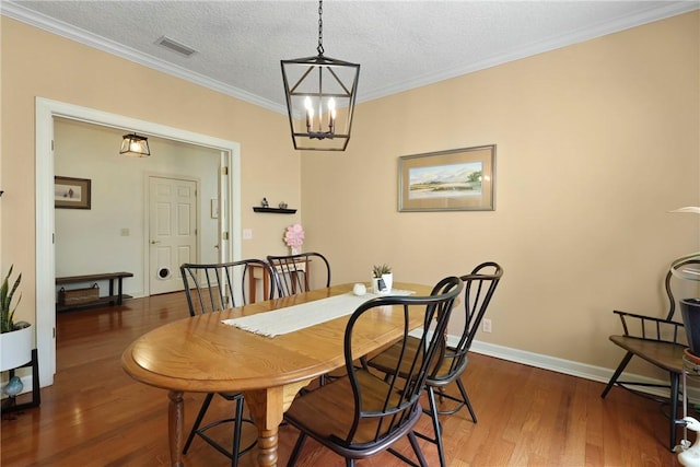 11 Niblick Ct, Saint Simons Island, GA 31522 - dining space with wood finished floors, a chandelier, a textured ceiling, ornamental molding, and baseboards