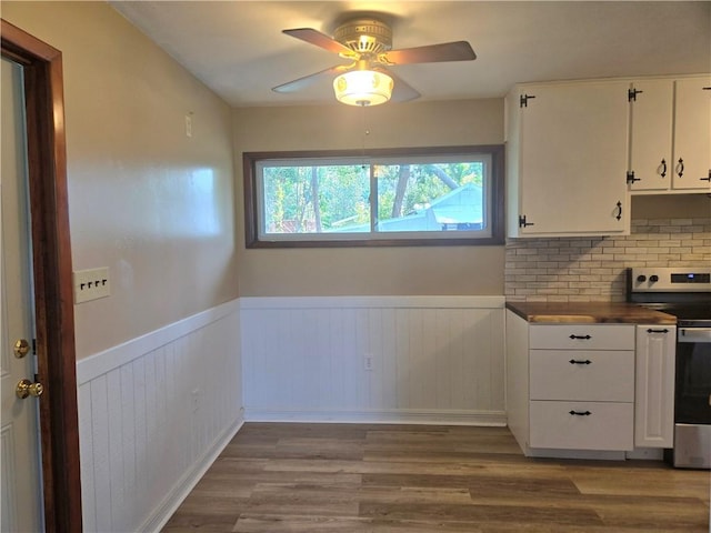 554 Blythe Island Dr, Brunswick, GA 31523 - kitchen with stainless steel range with electric cooktop, wood finished floors, white cabinets, a wainscoted wall, and a ceiling fan