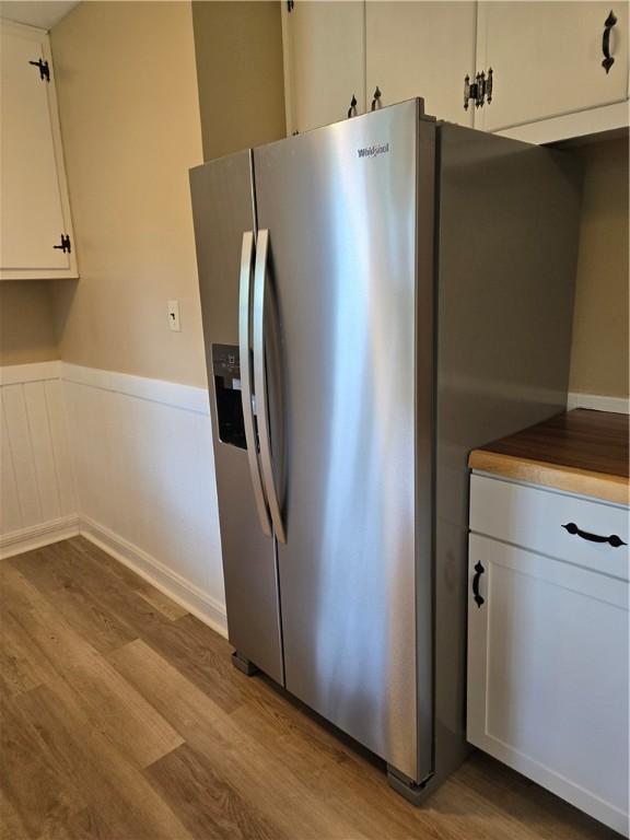 554 Blythe Island Dr, Brunswick, GA 31523 - kitchen featuring stainless steel refrigerator with ice dispenser, wood finished floors, white cabinetry, and a wainscoted wall