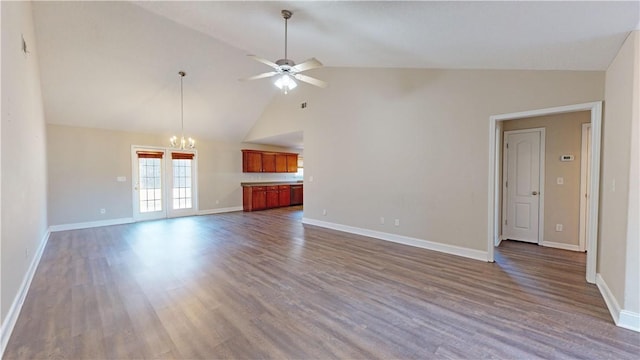 unfurnished living room featuring high vaulted ceiling, dark hardwood / wood-style flooring, and ceiling fan with notable chandelier