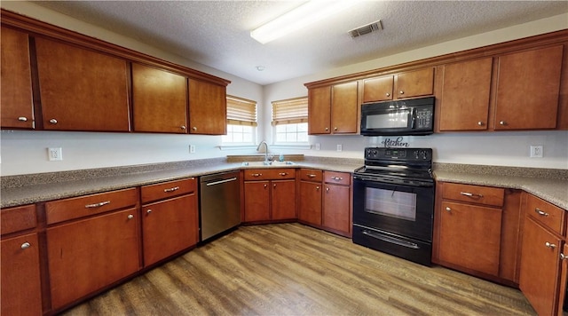 kitchen with sink, black appliances, a textured ceiling, and light wood-type flooring