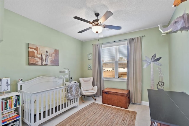 bedroom featuring a crib, ceiling fan, and a textured ceiling