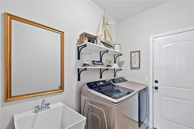 laundry area featuring sink, washer and dryer, and a textured ceiling