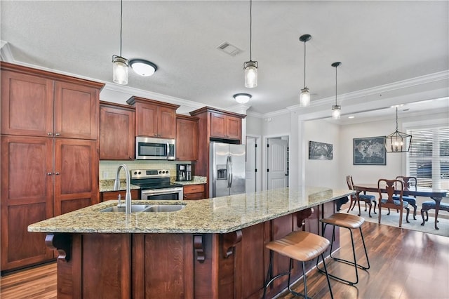 kitchen with stainless steel appliances, a breakfast bar area, hanging light fixtures, and a large island with sink