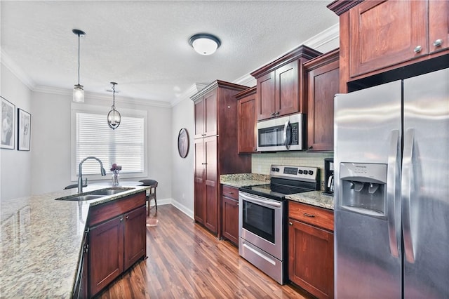 kitchen featuring pendant lighting, sink, light stone counters, and stainless steel appliances