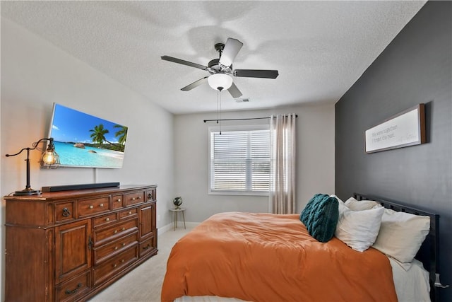 bedroom with ceiling fan, light colored carpet, and a textured ceiling