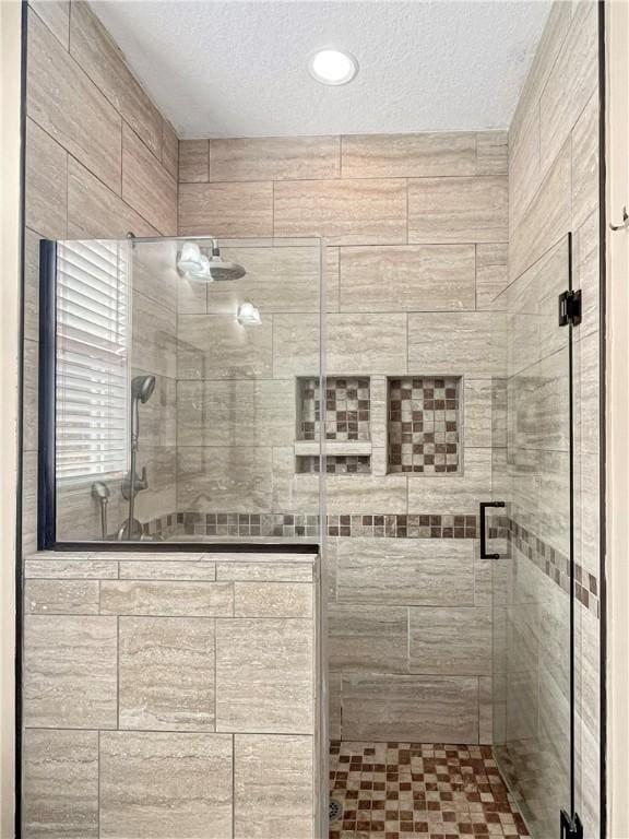 bathroom featuring a shower with shower door and a textured ceiling