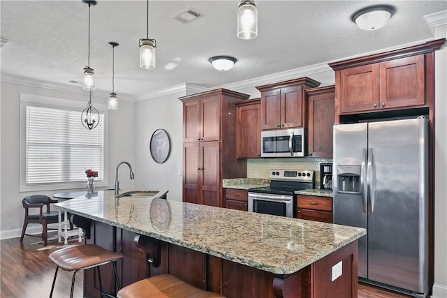 kitchen featuring appliances with stainless steel finishes, dark hardwood / wood-style floors, pendant lighting, sink, and a breakfast bar area